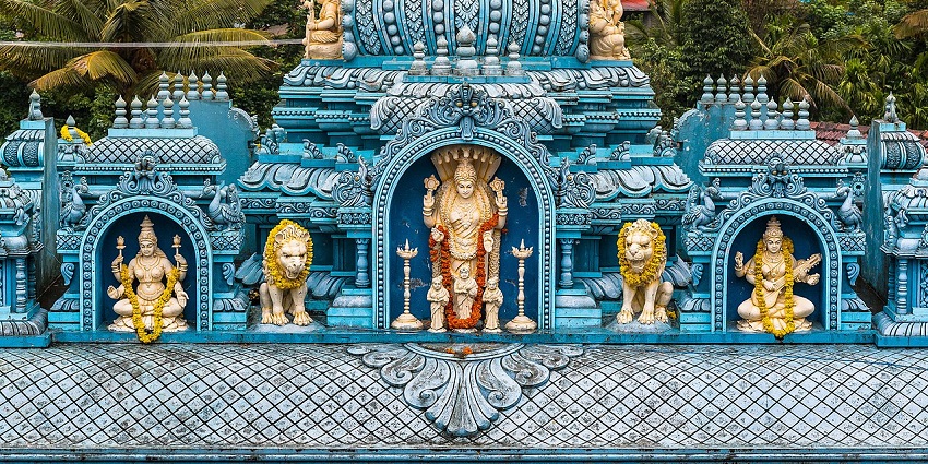 Colorful blue temple front with gods, and ornate architectural elements.