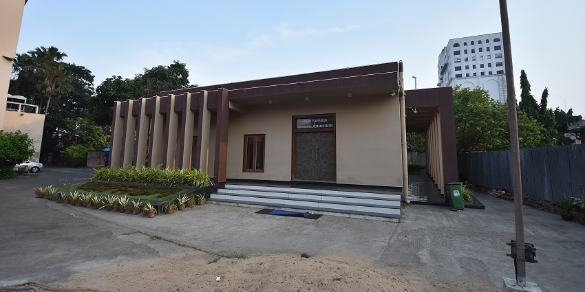 Modern single-storey building with vertical columns and a small garden in front.