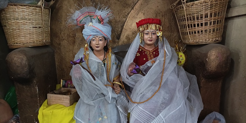 Traditional dressed dolls seated with veils and ornaments, surrounded by baskets and items.
