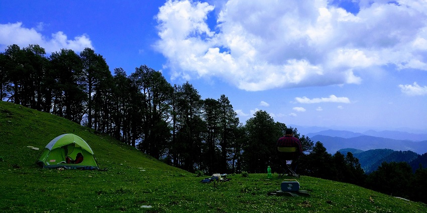 View of green meadows with camping tents at Jalori Pass, one of the places to visit near Tirthan valley.