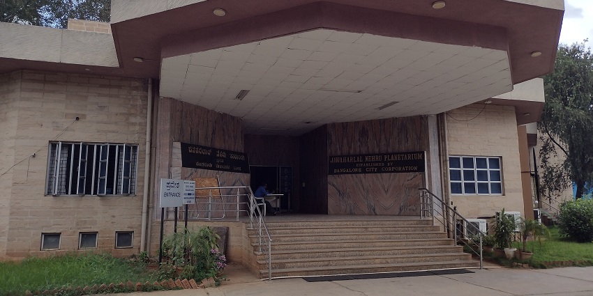 Jawaharlal Nehru Planetarium in Bangalore, with the stairs leading to the entrance and signboards.
