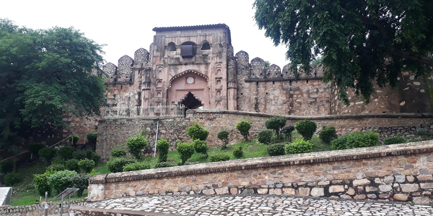 Distant entrance gate to Jhansi Fort with greenery, one of the historical places to visit near Datia.