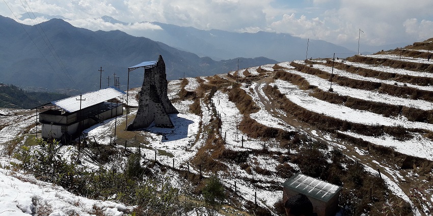 Snow-laden terrain at Kakani with trees and far hills beneath a cloudy sky.