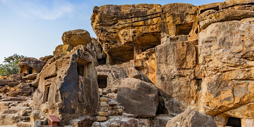Ancient Bhairi Caves carved into rocky cliffs surrounded by dense vegetation.