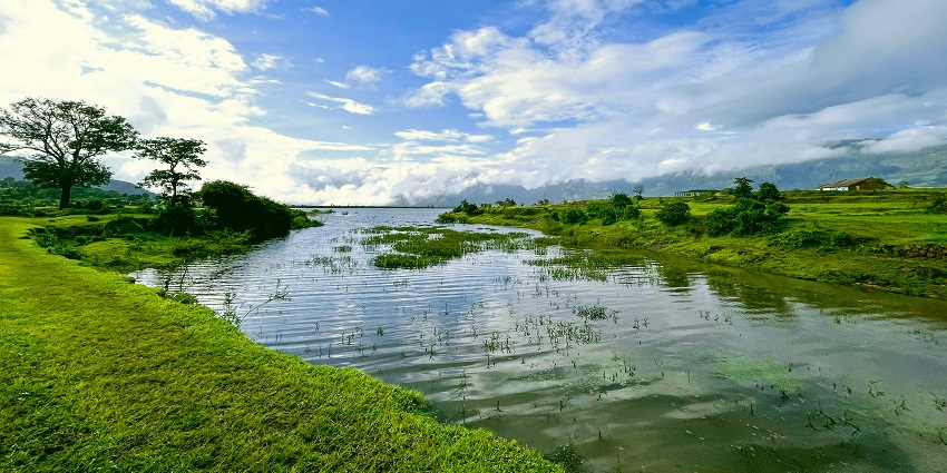 Calm Pawna Lake with surrounding hills and clear skies near Kamshet.