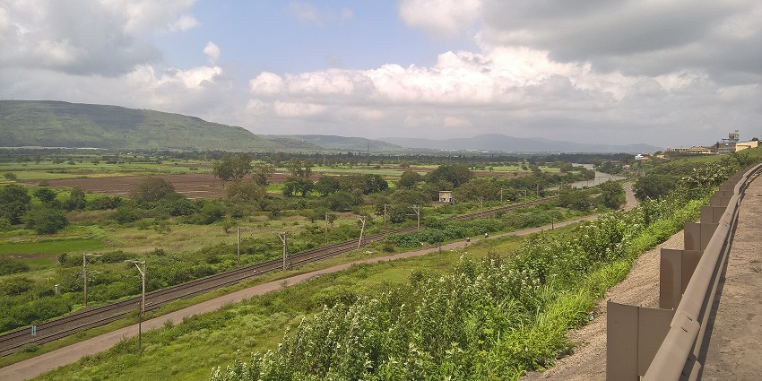 A man with his guide paraglides above the lush green terrains of Kamshet.
