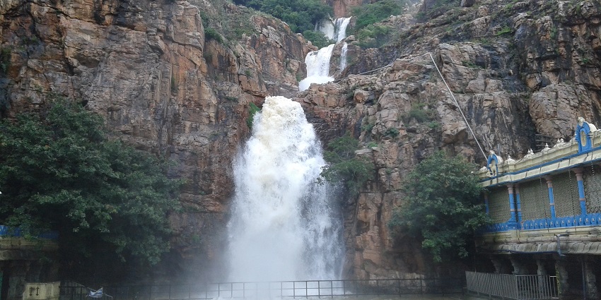 Majestic waterfall cascading down rugged cliffs next to a structure with blue railings.