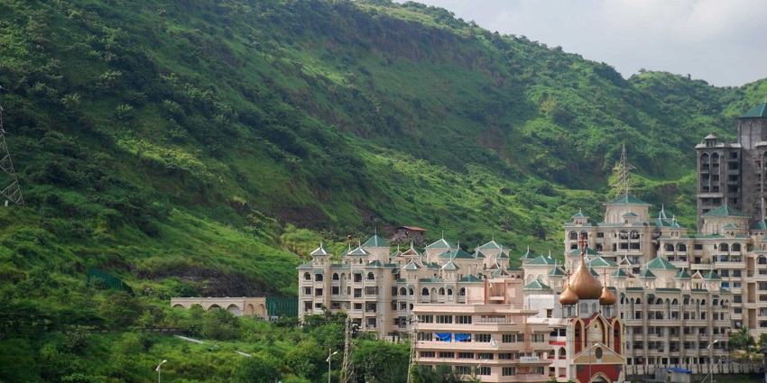 A scenic view of Kharghar Hills with green hills and residential buildings in the foreground.