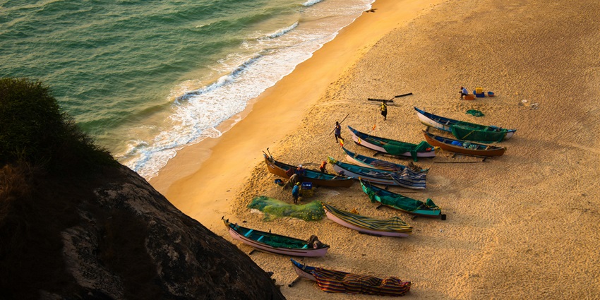 Peaceful view of Kodi Beach with gentle waves, soft sand, and a clear blue sky.