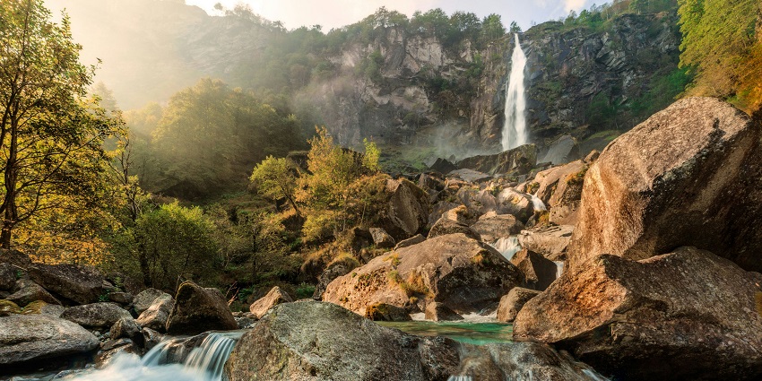 Water cascading down rocks at Kolad waterfall surrounded by lush green vegetation.