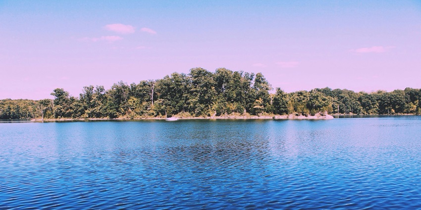 Laxmi Tal lake with still water and surrounding trees reflecting a quiet, natural atmosphere.