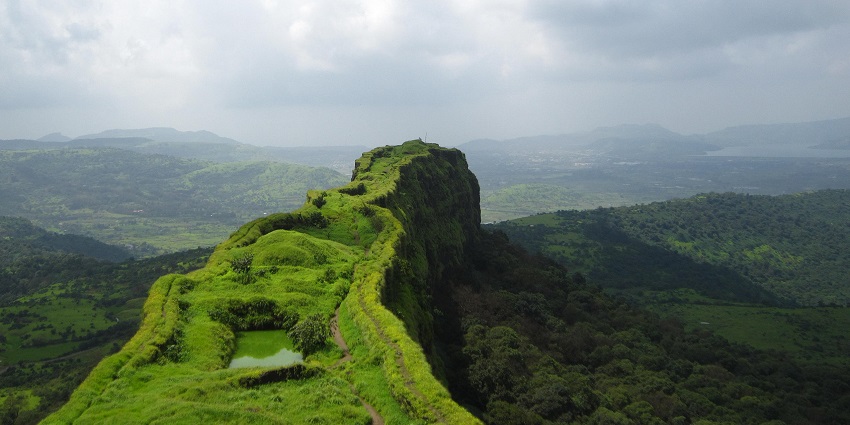 Lohagad Fort’s long, narrow ridge is covered in green grass, overlooking hills, among the places to visit near Khandala.
