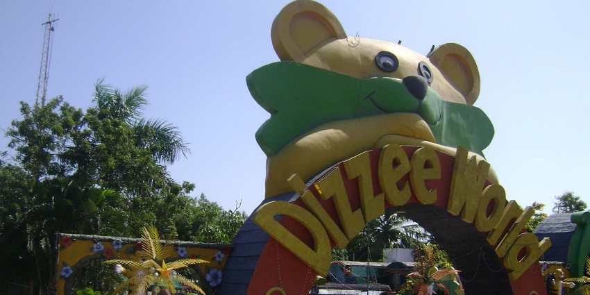 Colourful entrance arch of MGM Dizzee World with a giant bear figure and lush greenery