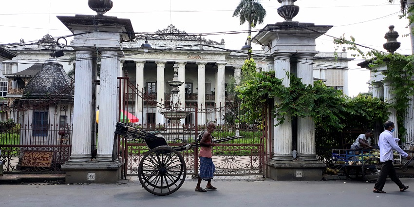 A man pulls a hand-driven cart in front of the entrance of the Marble Palace near Eco Park.