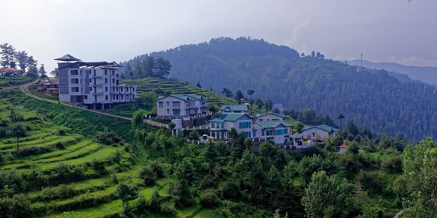 Mashobra's picturesque landscape is spotted with lush green hills and buildings situated in the valley below