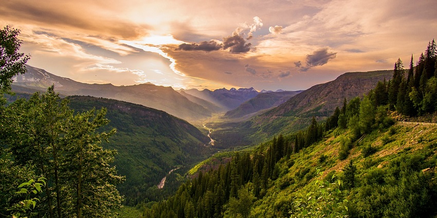 Cloudy sky over green mountains at dawn, creating a peaceful and serene landscape.