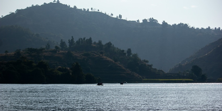 View of Tikar Taal, a lake surrounded by lush green rocky terrain in the Morni Hills.