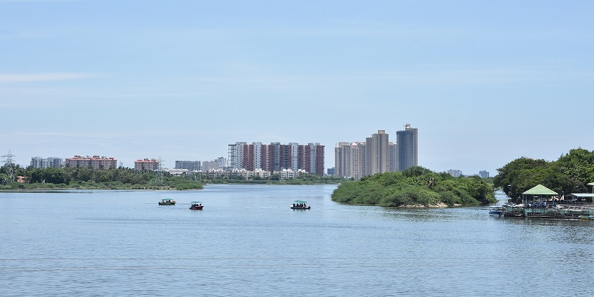 Tourists enjoy boating in the Muttukadu Backwaters with tall skyscrapers in the background