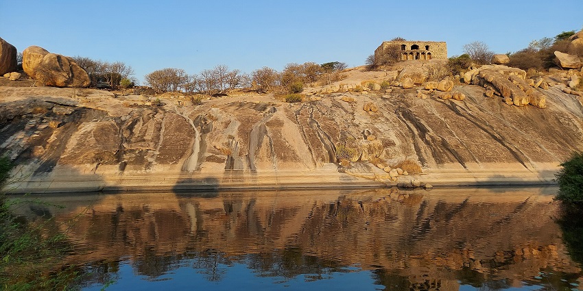 Nalgonda’s Devarakonda Fort is perched atop a hill with a still pond in the foreground.

