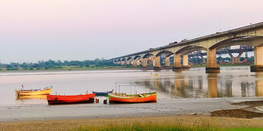 Narmada Park with river view, boats near the shore, and Sardar Patel Bridge in the background.