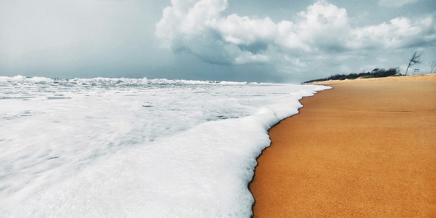 Waves crashing gently on the sandy shores of Puri Beach under a clear sky.