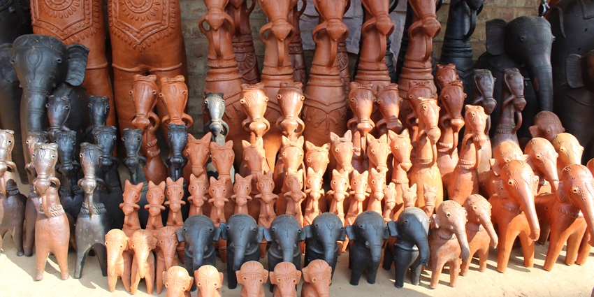 Rows of handcrafted terracotta and clay horse and elephant figurines are arranged for display.