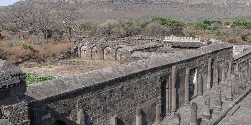 Historic stone fort situated on a hilltop surrounded by dense greenery under a clear sky.
