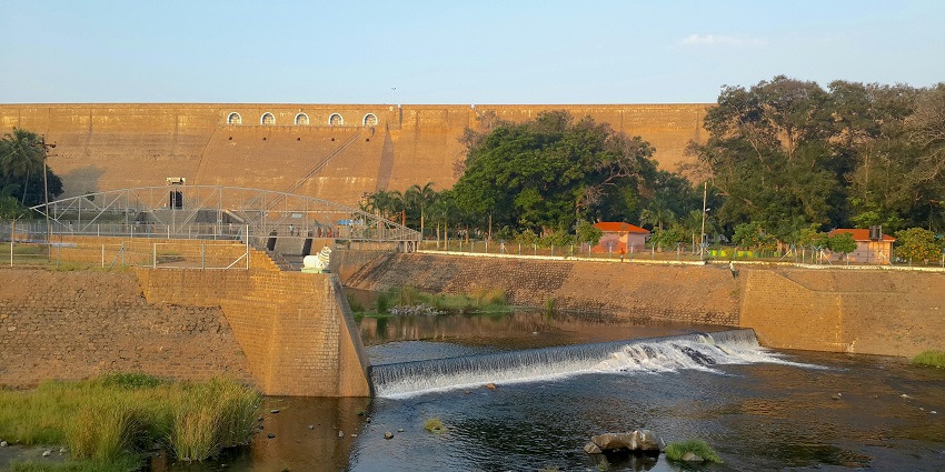 Perumpallam Dam with calm water, surrounding hills, and open sky in the background.