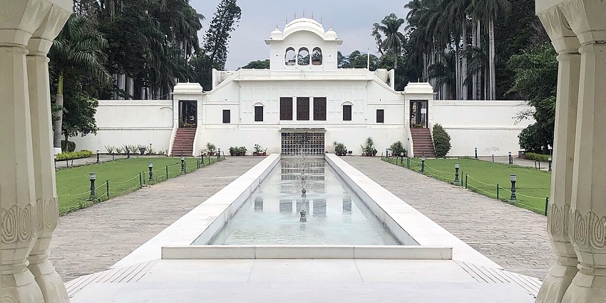 A historic Mughal-style garden with symmetrical lawns, fountains, and terraced walkways.
