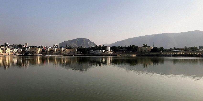 Serene Pushkar Lake with distant buildings, one of the peaceful places to visit near Jaipur for 1 day.