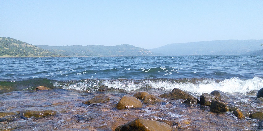 Waves crash on pebbles at Radhanagari Dam, one of the places to visit near Ichalkaranji.
