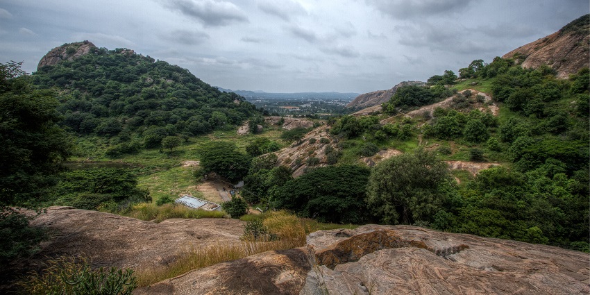 View of scenic Ramanagara Hills with rocky terrain and greenery and cloudy skies in the background, one of the places to visit near Electronic City.