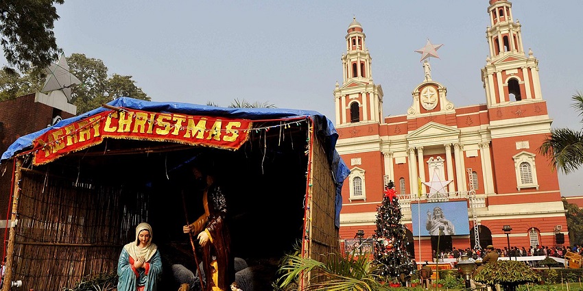 A Christmas nativity scene and festive decorations are displayed outside a historic cathedral church.
