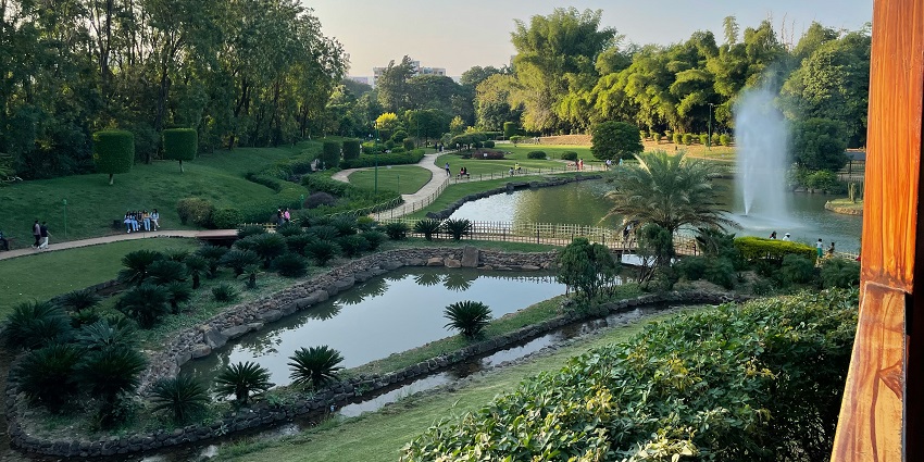 Lush green lawns and walking paths at Sagar Vihar Garden with shaded trees.
