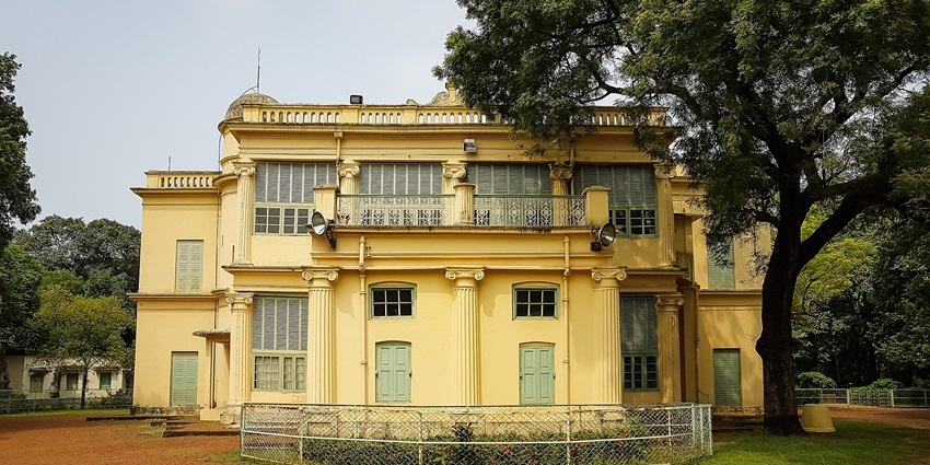 Santiniketan Griha in West Bengal with old indian architectural buildings and tall green trees.