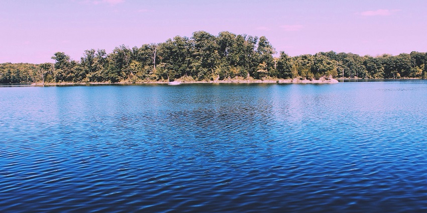 Serene view of Santragachi Jheel with calm water reflections and lush greenery.