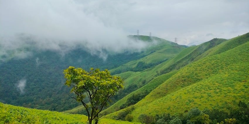 Savandurga Hill with expansive green hills and natural surroundings in the distance.

