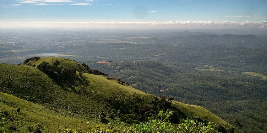 Scenic view from the summit of Mullayanagiri Peak with rolling hills and clear skies.