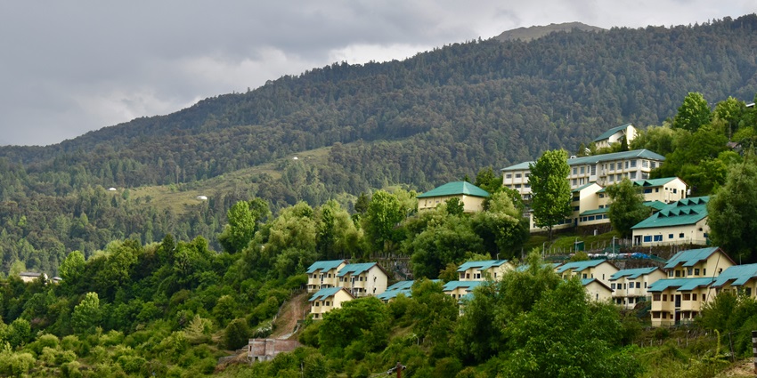 A mesmerising view of the Shitlakhet Village with houses surrounded by lush green mountains.