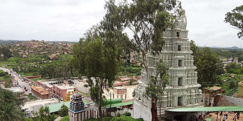 Temple tower amid trees and rocky hills is among scenic places to visit near Dabaspet.