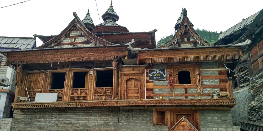 Ornate wooden temple with detailed carvings standing atop a sturdy stone foundation