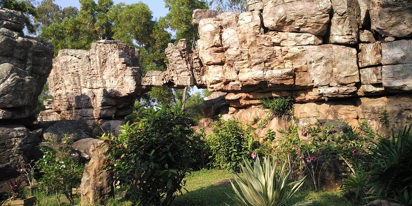 Large natural rock formations surrounded by green plants and flowering garden landscape, one of the best places to visit near Tirupati in one day.