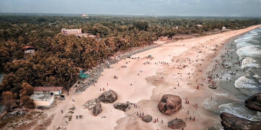 Serene coastal view of Someshwara Beach with rocky shore and gentle blue waves.