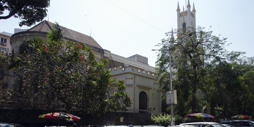 St Thomas Cathedral in Mumbai with a white Gothic-style tower and bell under a blue sky