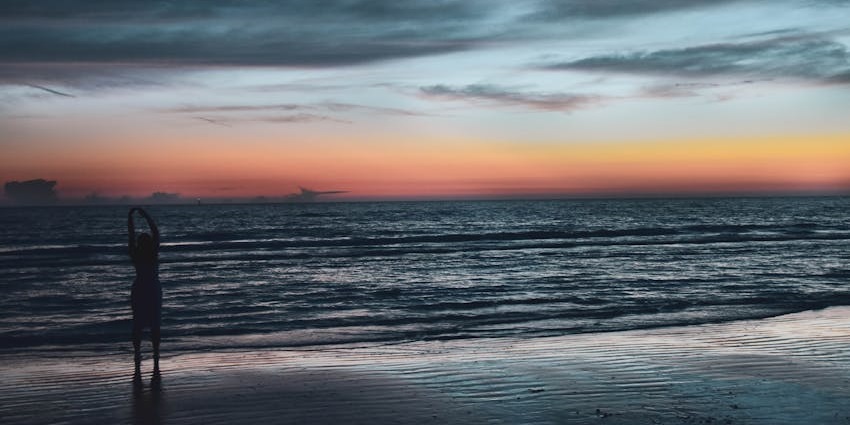 Beach in the evening with a woman standing on the shore, low tide waves, one of the best things to see in Ponte Vedra Beach FL.