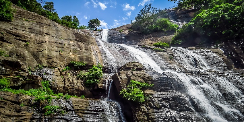 Vaideki Falls cascade over rocky terrain with clear water flowing down.