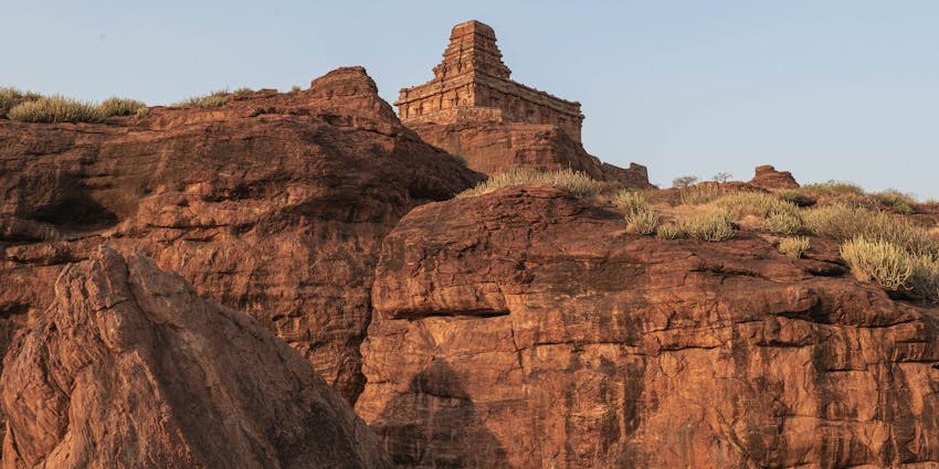 Ancient rock-cut Vaikunta Caves are surrounded by a natural landscape under the sky.
