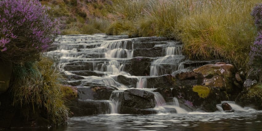 Vajrapoha Falls cascade through rocky terrain, surrounded by lush greenery and forest views.