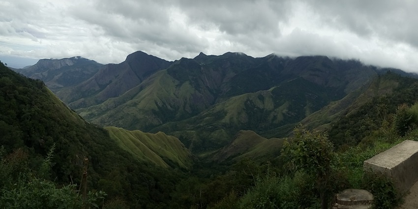 A panoramic view of Kerala's lush green hills, showcasing undulating terrain and dense forests.