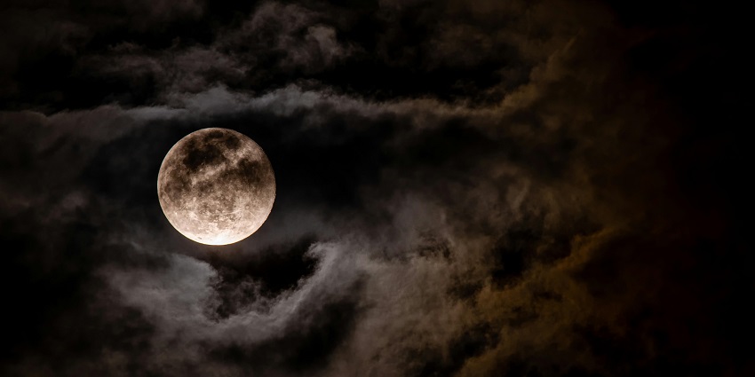 Bright full moon shining through a cloudy night sky over the Rann of Kutch.
